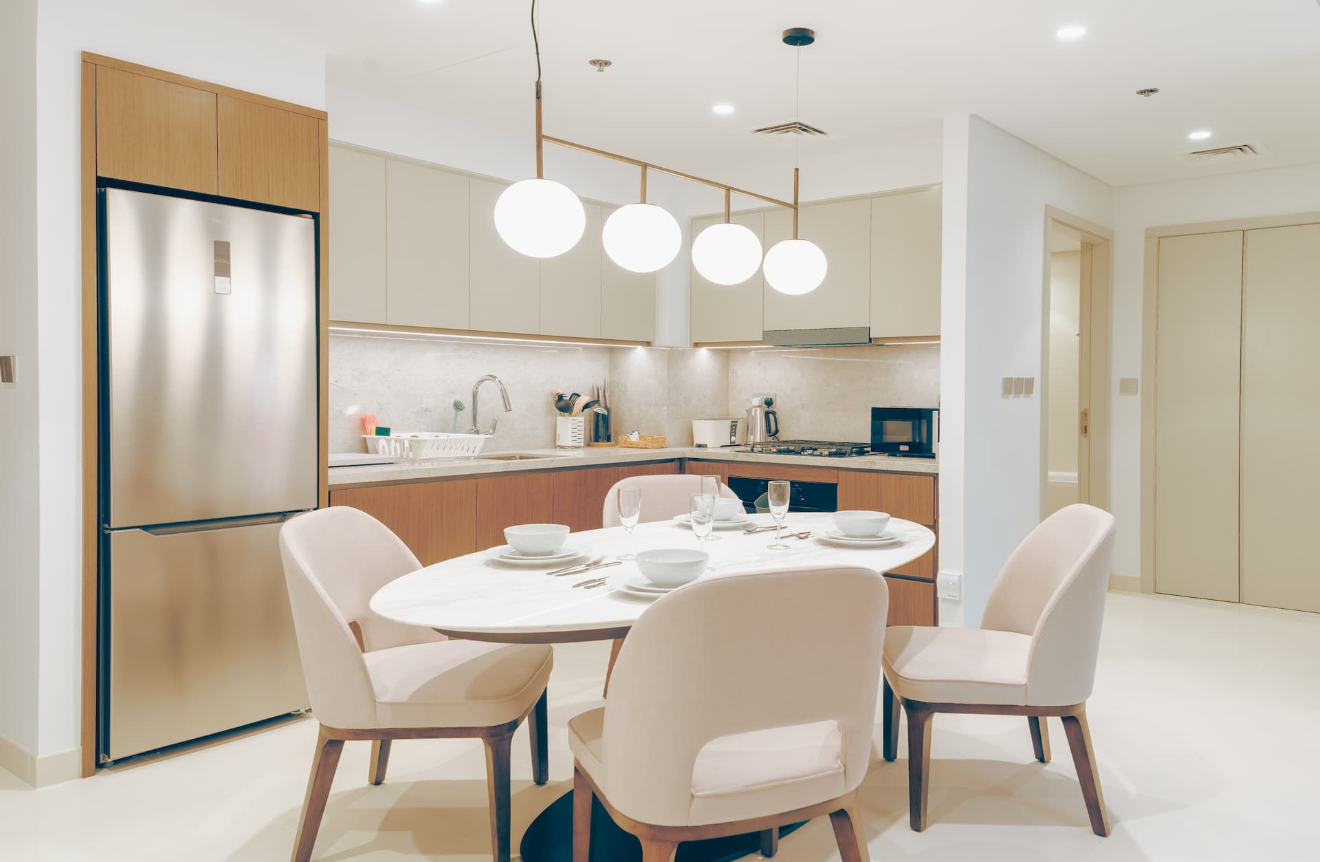 Dining area with globe pendant lights and fully equipped kitchen in one bedroom beachfront apartment Dubai — YOUR STAY Apartments