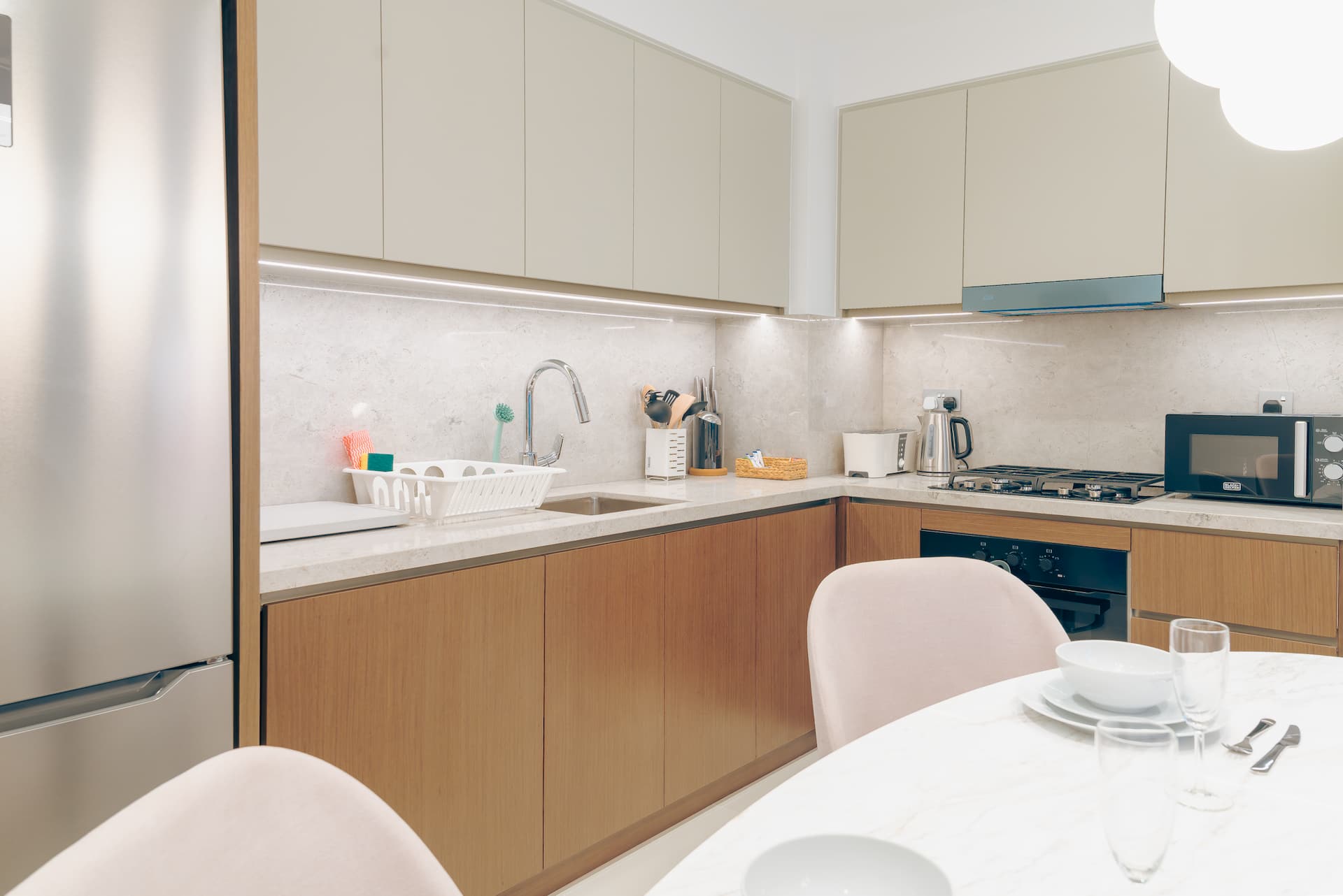 Modern fully equipped kitchen with marble countertops and stainless steel appliances in one bedroom serviced apartment Dubai