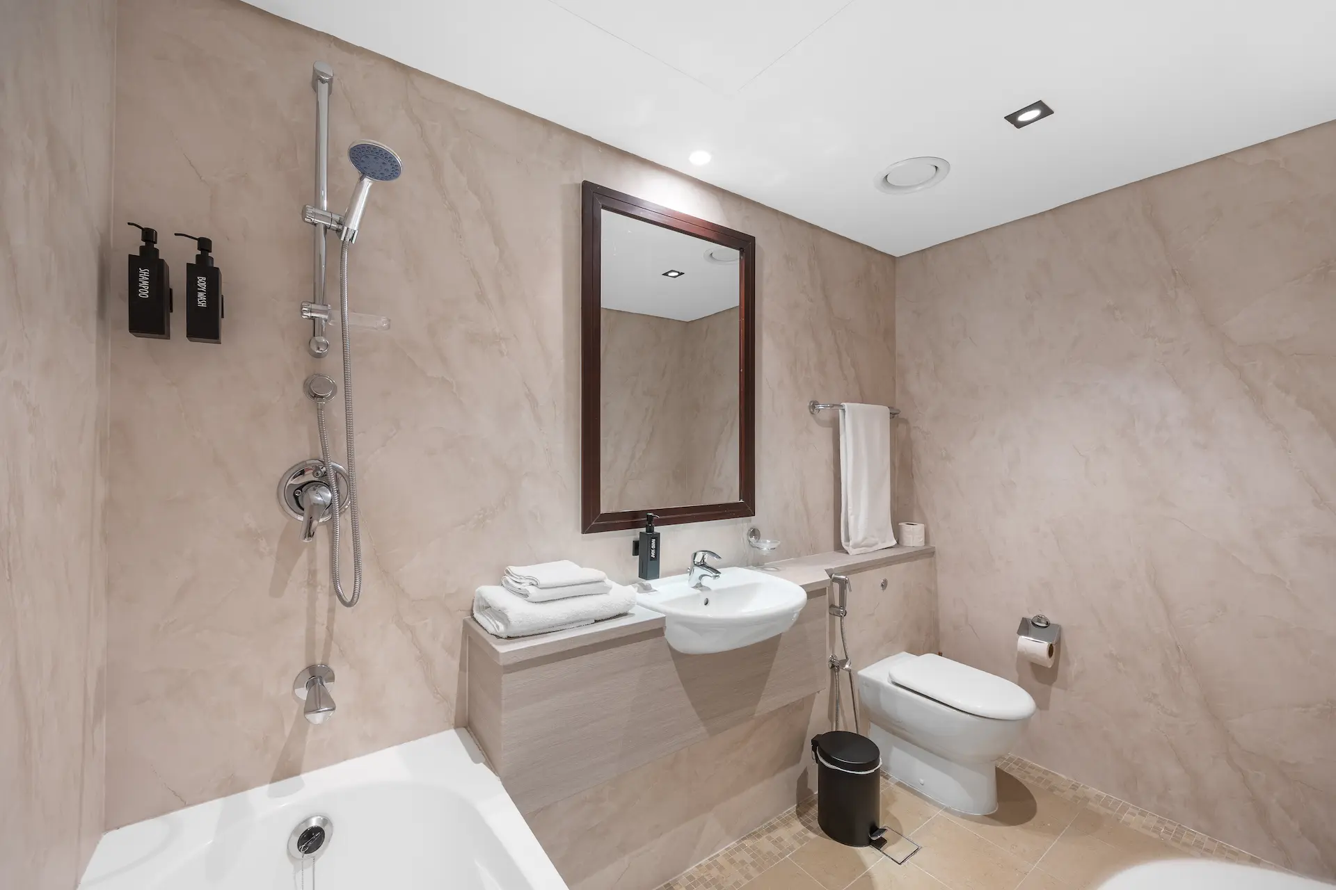 Full bathroom with soaking bathtub and marble walls at Sky Gardens DIFC Dubai