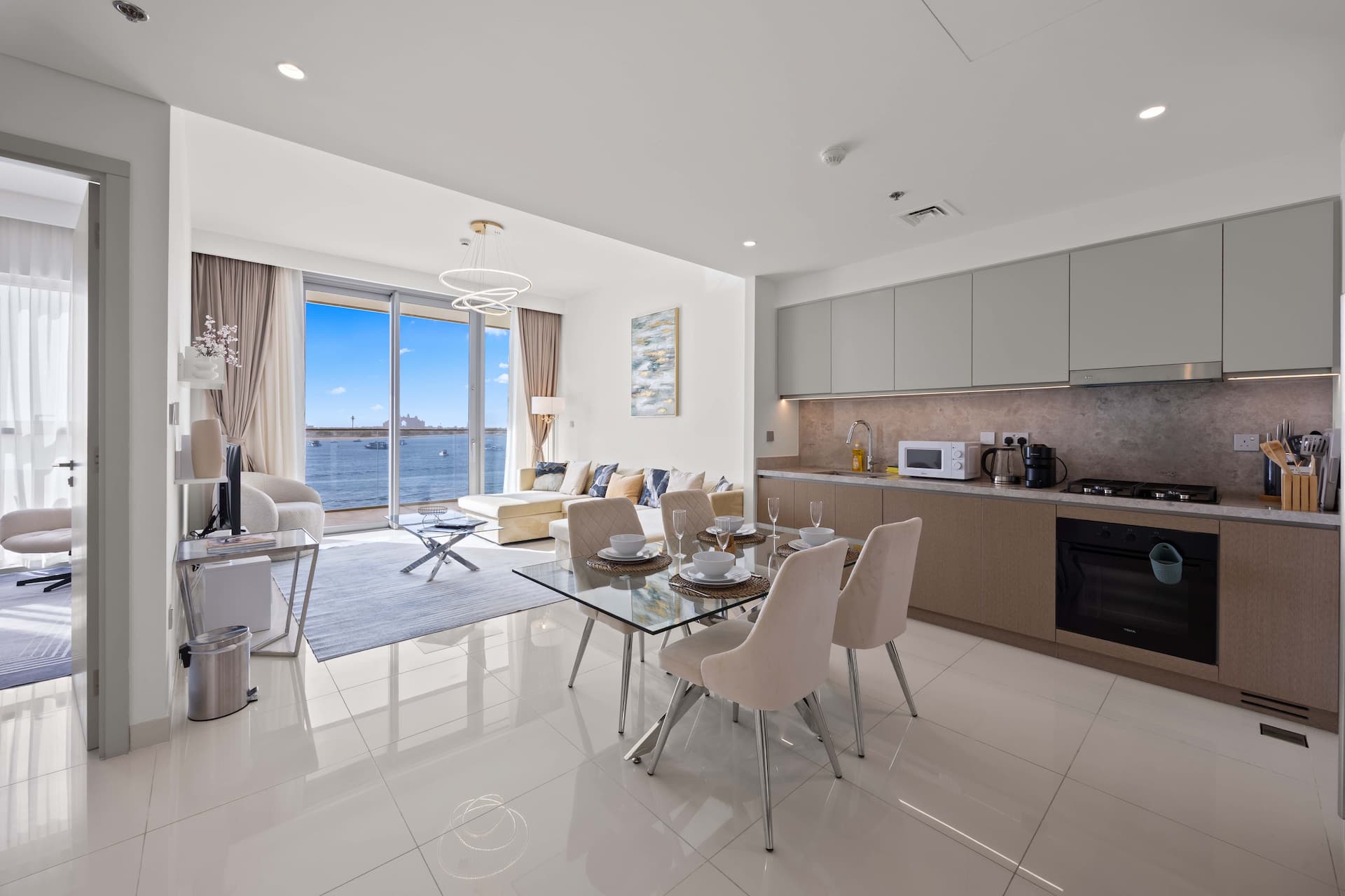 Open-plan living and dining area with fully equipped kitchen in two bedroom beachfront apartment Dubai — sea view serviced apartment YOUR STAY