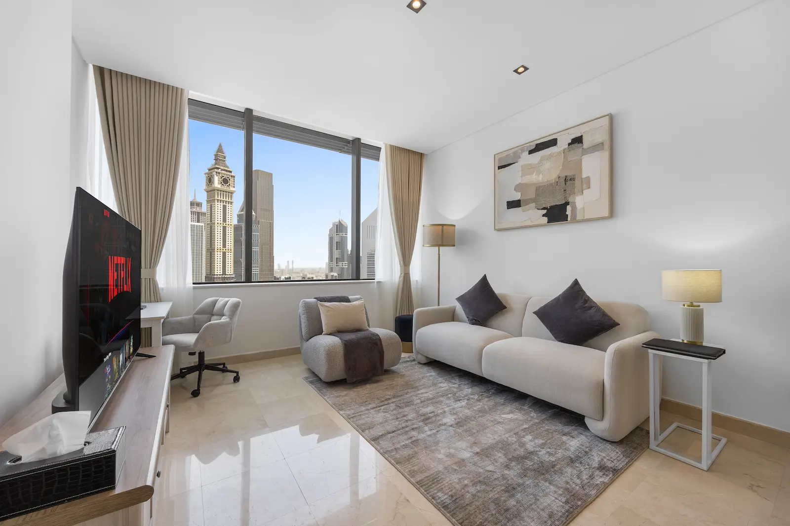 Lounge with Emirates Towers skyline view, workspace desk and Netflix smart TV at Sky Gardens DIFC Dubai